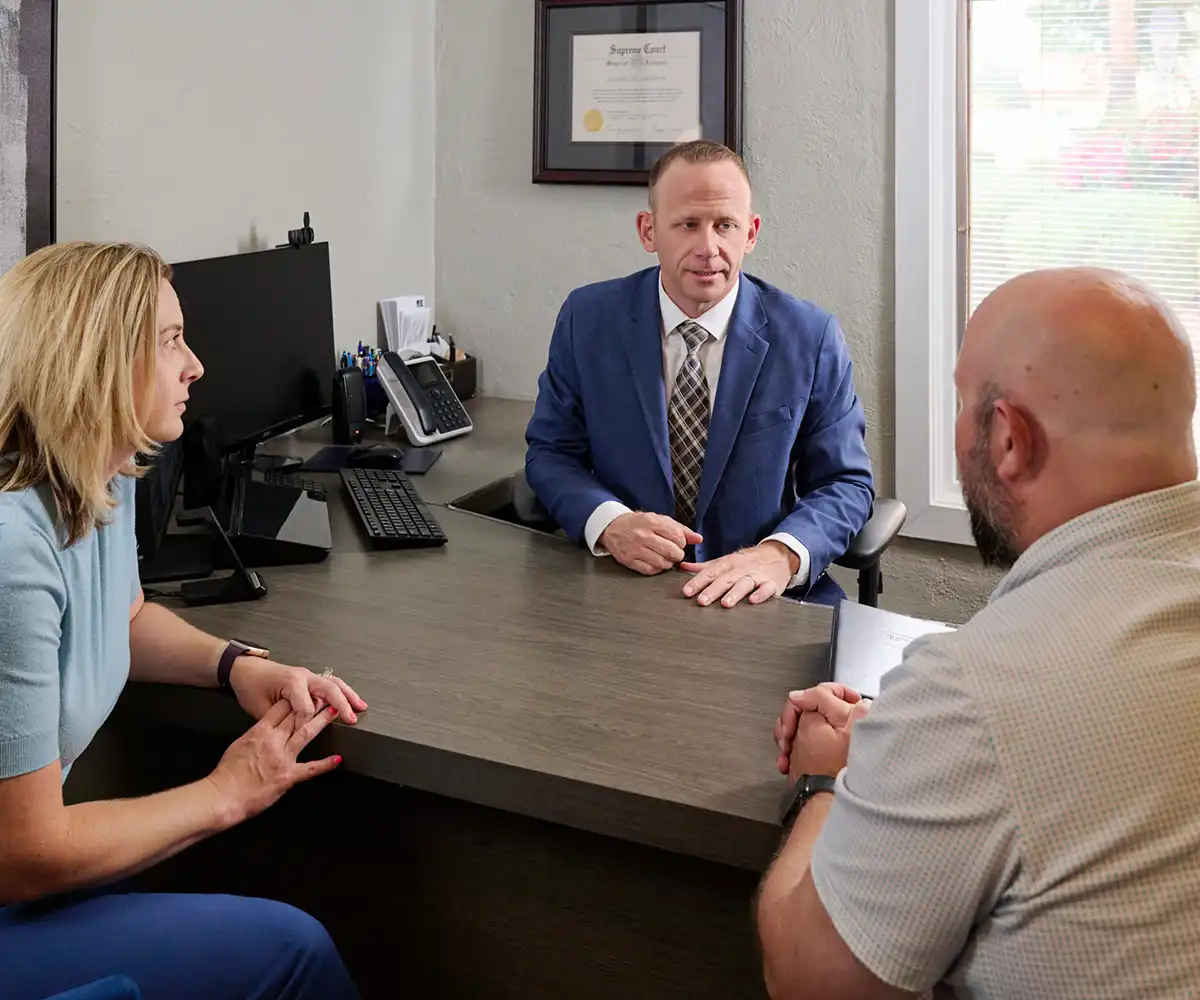 Jeffrey Grayson seated at his office desk speaking with two clients